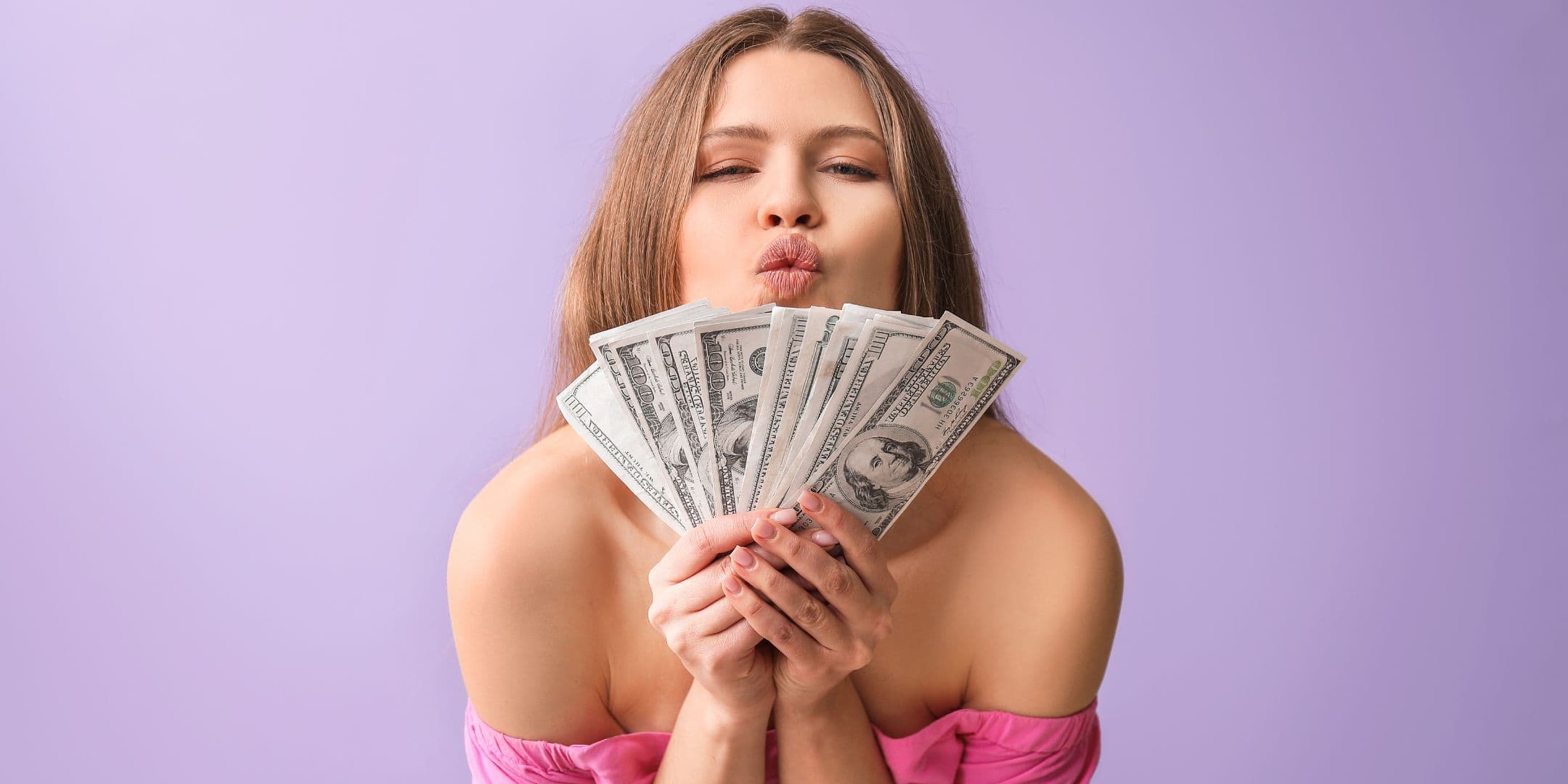 a young woman kissing at the camera holding money on a lavender background, hero image for article on revenge savings