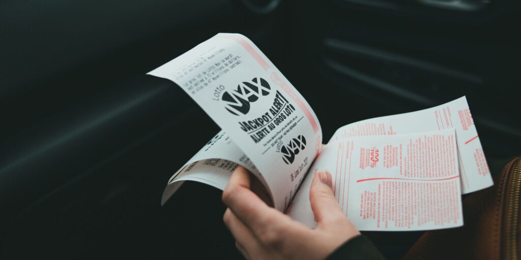 person holding lottery ticket and thinking about what to do after winning the lottery